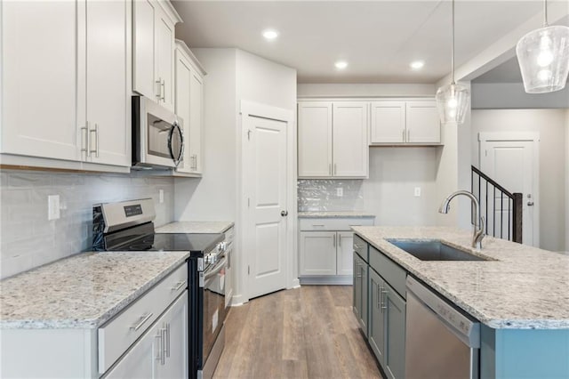 4045 Links Blvd, Jefferson, GA 30549 - kitchen featuring appliances with stainless steel finishes, a sink, wood finished floors, decorative backsplash, and hanging light fixtures