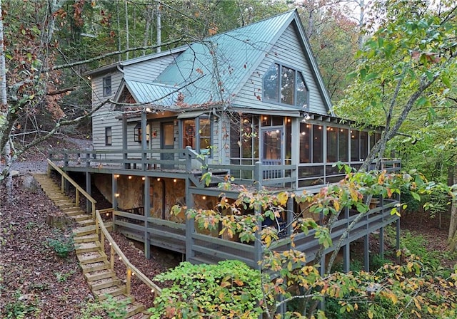 rear view of house featuring a sunroom and a wooden deck