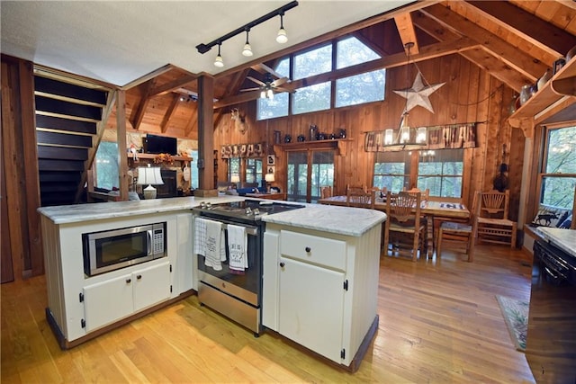 kitchen with vaulted ceiling with beams, stainless steel appliances, kitchen peninsula, and white cabinetry