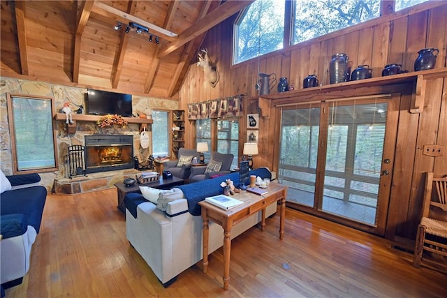 living room with wood ceiling, wood-type flooring, beam ceiling, high vaulted ceiling, and a stone fireplace