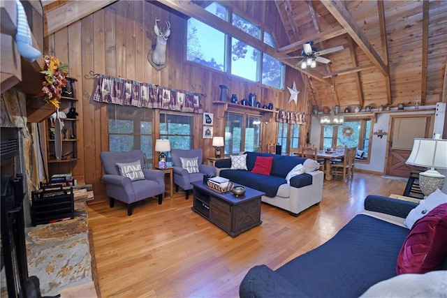 living room featuring light wood-type flooring, wooden walls, ceiling fan, and beamed ceiling