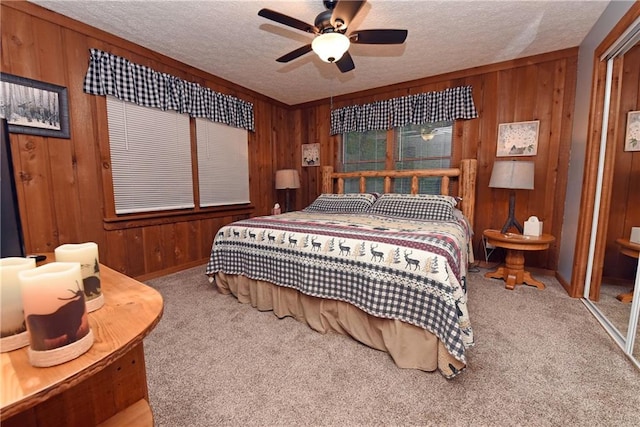 bedroom featuring ceiling fan, a textured ceiling, wooden walls, and carpet