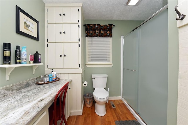 bathroom with walk in shower, hardwood / wood-style flooring, vanity, and toilet