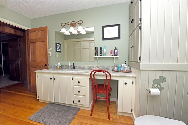 bathroom with a textured ceiling, wood-type flooring, vanity, and toilet