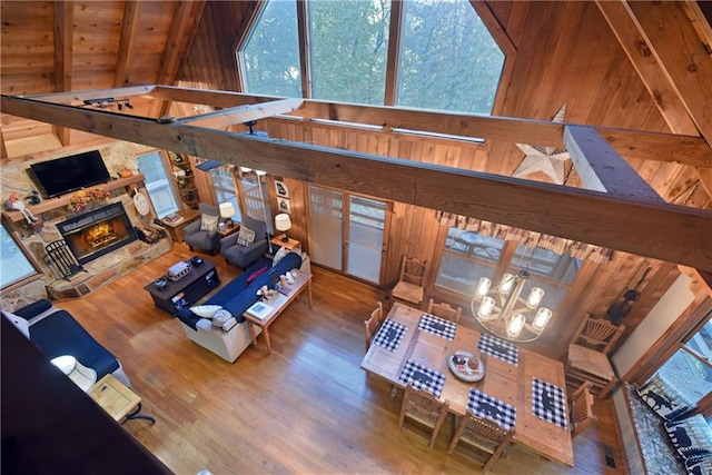 living room with wood ceiling, wood-type flooring, beam ceiling, a fireplace, and wooden walls