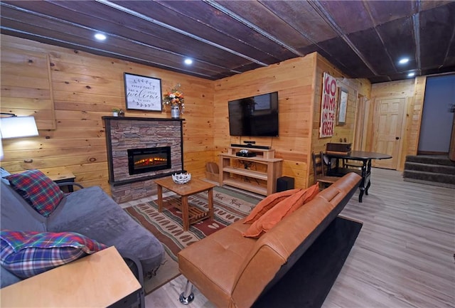 living room with hardwood / wood-style flooring, wooden walls, and a fireplace