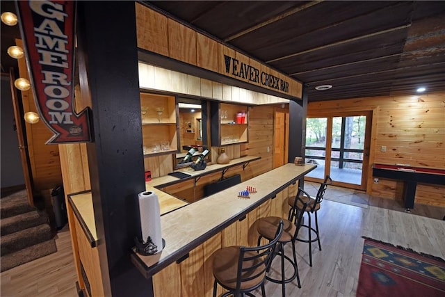 bar featuring light hardwood / wood-style flooring and wood walls