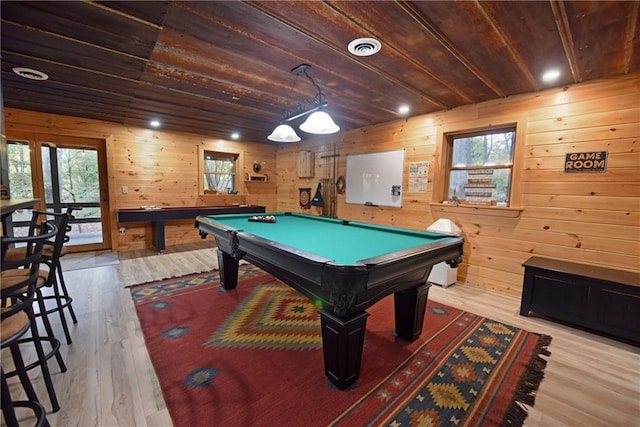 rec room with light hardwood / wood-style flooring, plenty of natural light, and wood walls