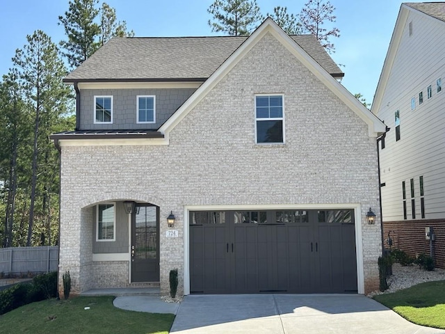 view of front of property featuring a standing seam roof, an attached garage, brick siding, and driveway