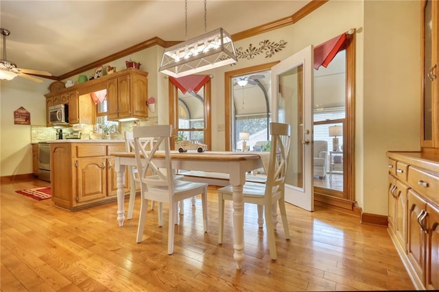 dining area with ceiling fan, ornamental molding, and light wood-type flooring