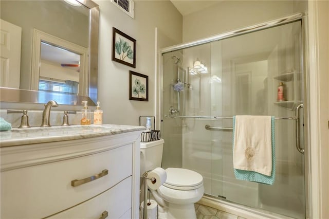 bathroom featuring tile patterned floors, vanity, toilet, and a shower with shower door