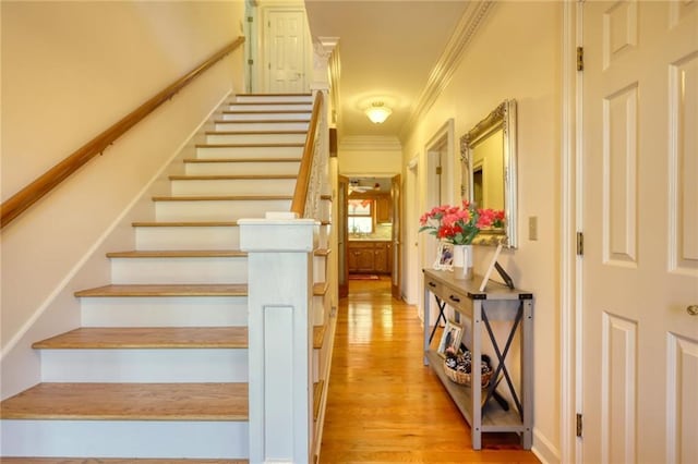 stairs with hardwood / wood-style flooring and ornamental molding