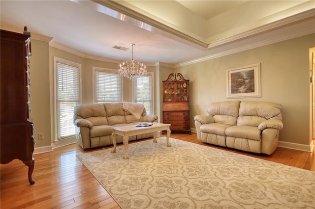 living room with ornamental molding, a notable chandelier, and light wood-type flooring