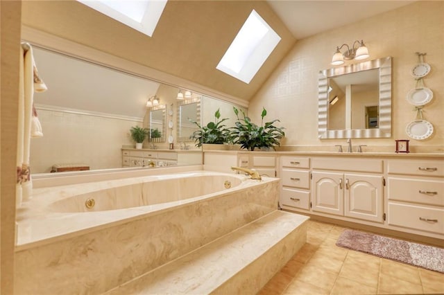 bathroom with vaulted ceiling with skylight, tile patterned flooring, vanity, and tiled tub