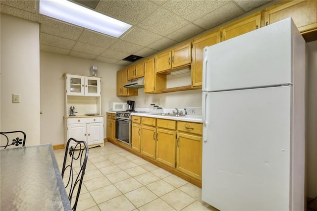 kitchen featuring a drop ceiling, light tile patterned floors, white appliances, and sink