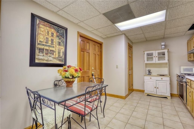 dining space featuring a paneled ceiling and light tile patterned floors