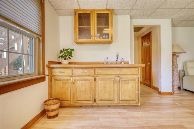 bar with light hardwood / wood-style flooring and a drop ceiling