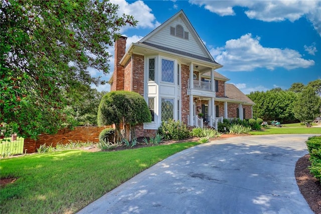 view of front of house with a front yard and a balcony