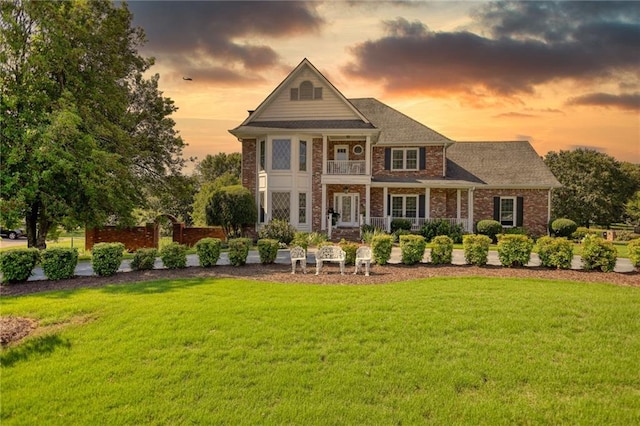 view of front of house with a balcony and a lawn