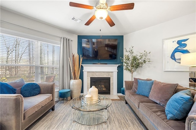 living area with visible vents, ceiling fan, and a high end fireplace