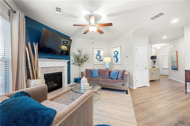 living area featuring visible vents, a fireplace, a ceiling fan, and wood finished floors