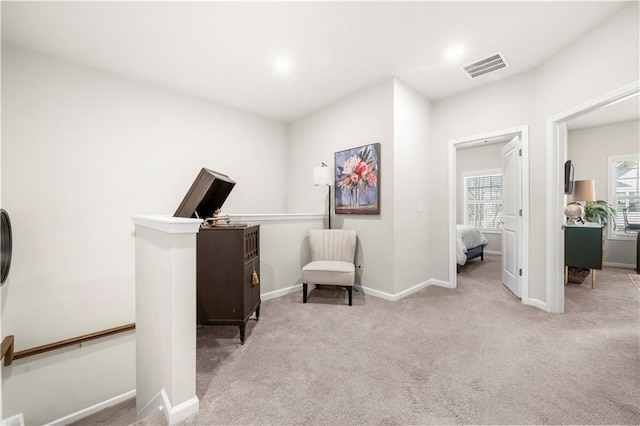 sitting room featuring visible vents, baseboards, carpet, and an upstairs landing