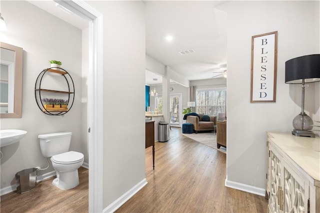 hall featuring wood finished floors, visible vents, and baseboards