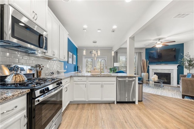 kitchen featuring visible vents, a sink, white cabinetry, light wood-style floors, and appliances with stainless steel finishes