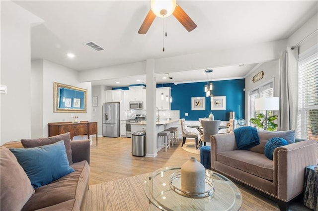 living room featuring visible vents, ceiling fan, and light wood-style flooring