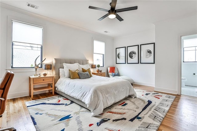 bedroom featuring ensuite bathroom, hardwood / wood-style floors, and multiple windows