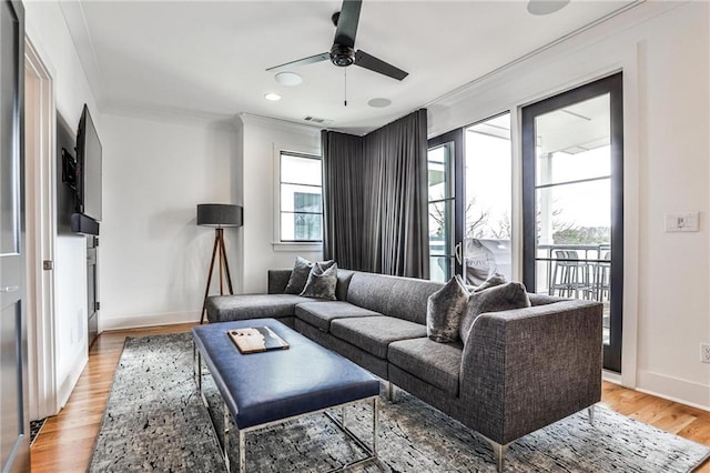 living room with crown molding, ceiling fan, plenty of natural light, and light hardwood / wood-style flooring