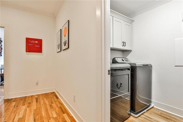 laundry room featuring crown molding, cabinets, separate washer and dryer, and light hardwood / wood-style floors