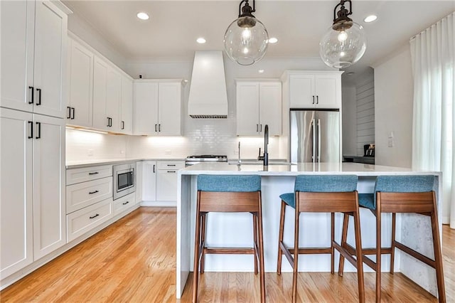 kitchen with premium range hood, white cabinetry, appliances with stainless steel finishes, and pendant lighting