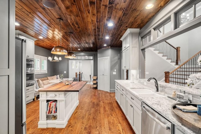 kitchen featuring appliances with stainless steel finishes, light wood-type flooring, wood counters, wooden ceiling, and white cabinets