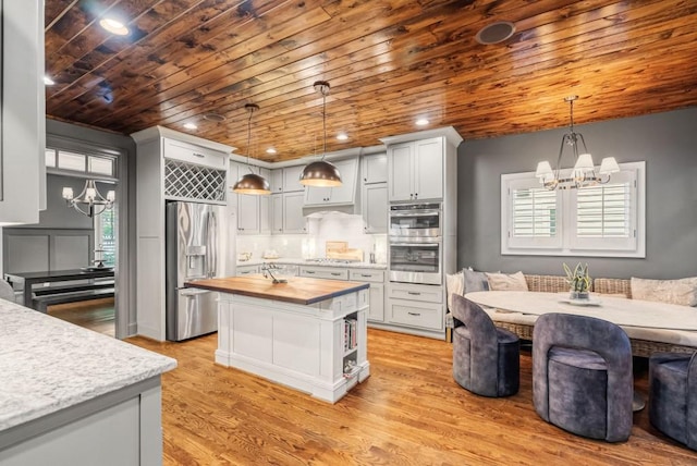 kitchen featuring a notable chandelier, wood counters, pendant lighting, and stainless steel appliances