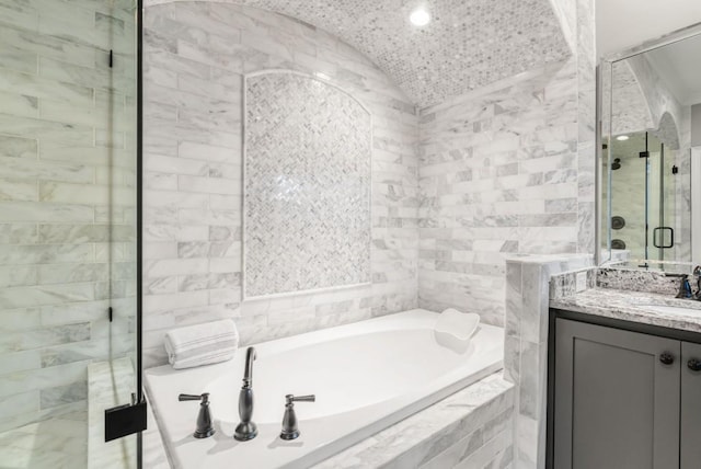 bathroom with vanity, tile walls, vaulted ceiling, and separate shower and tub