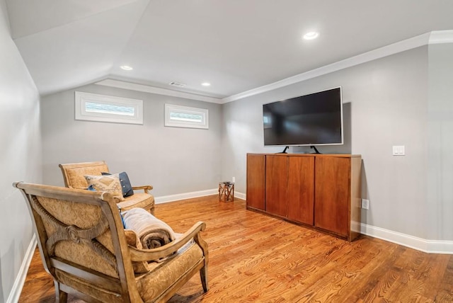 living area with crown molding, vaulted ceiling, and light hardwood / wood-style floors