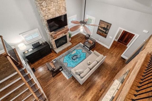 living room featuring dark wood-type flooring, a fireplace, high vaulted ceiling, and ceiling fan