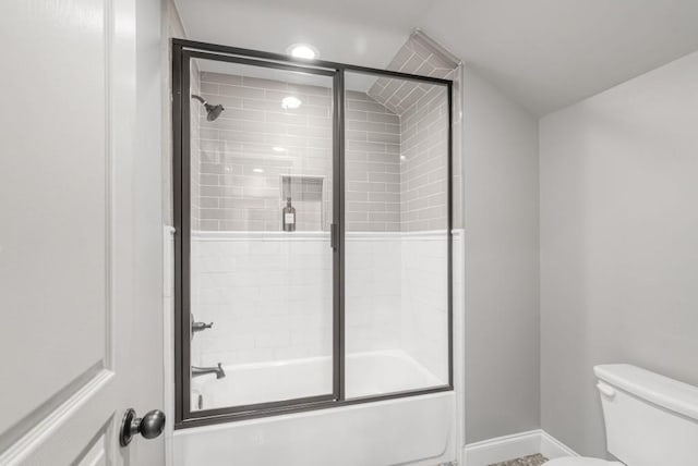 bathroom with toilet and bath / shower combo with glass door