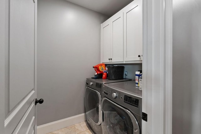 washroom featuring cabinets, light tile patterned flooring, and washer and clothes dryer