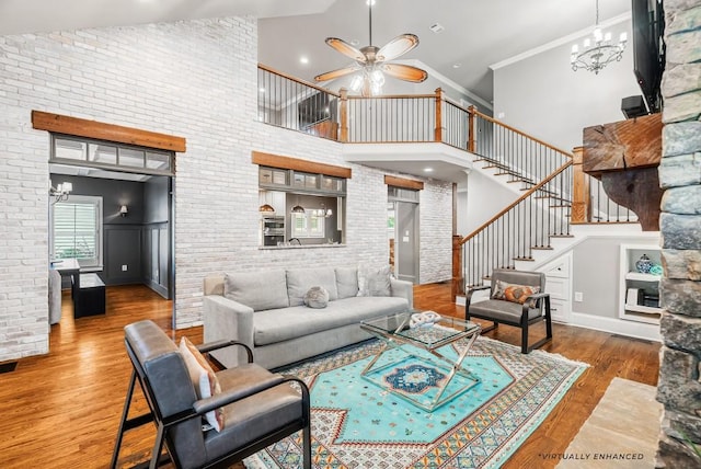 living room with brick wall, hardwood / wood-style floors, crown molding, high vaulted ceiling, and ceiling fan