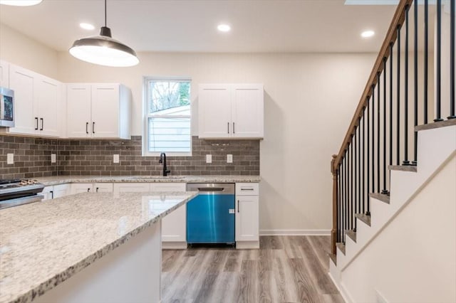 kitchen featuring appliances with stainless steel finishes, decorative light fixtures, sink, white cabinets, and light stone counters