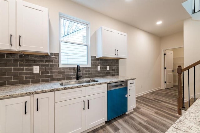 kitchen featuring sink, dishwasher, white cabinetry, light stone counters, and light hardwood / wood-style floors