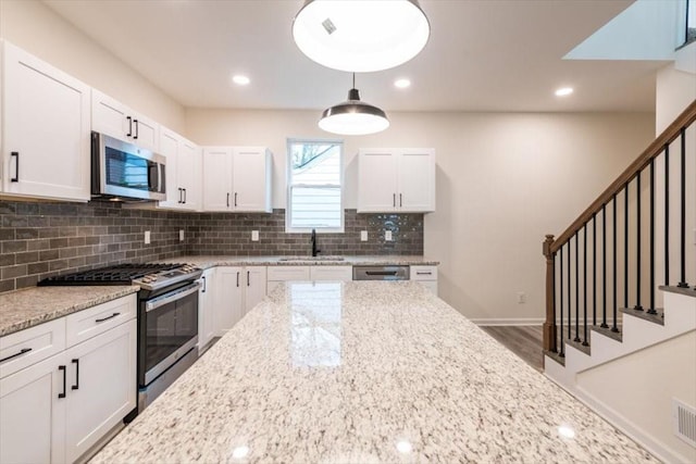 kitchen with light stone counters, appliances with stainless steel finishes, and white cabinets