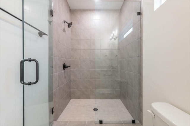 bathroom featuring toilet and a shower with shower door