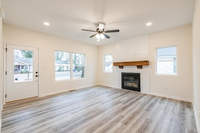 unfurnished living room featuring plenty of natural light, a large fireplace, and light wood-type flooring