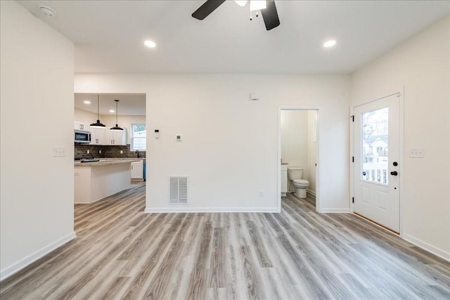 living room with ceiling fan, sink, and light hardwood / wood-style floors