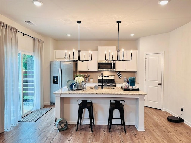 135 Softwood Ct, Dawsonville, GA 30534 - kitchen featuring stainless steel appliances, light wood finished floors, white cabinetry, a kitchen bar, and recessed lighting