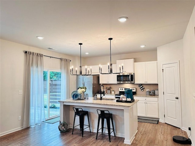 135 Softwood Ct, Dawsonville, GA 30534 - kitchen with stainless steel appliances, light wood finished floors, white cabinets, an island with sink, and recessed lighting