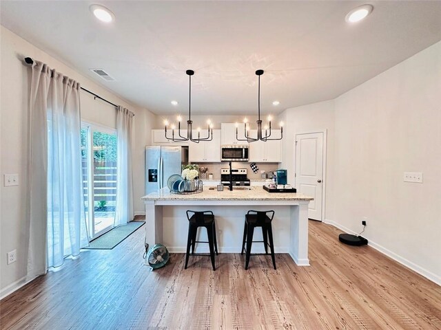135 Softwood Ct, Dawsonville, GA 30534 - kitchen featuring stainless steel appliances, a chandelier, light wood-type flooring, a kitchen bar, and recessed lighting